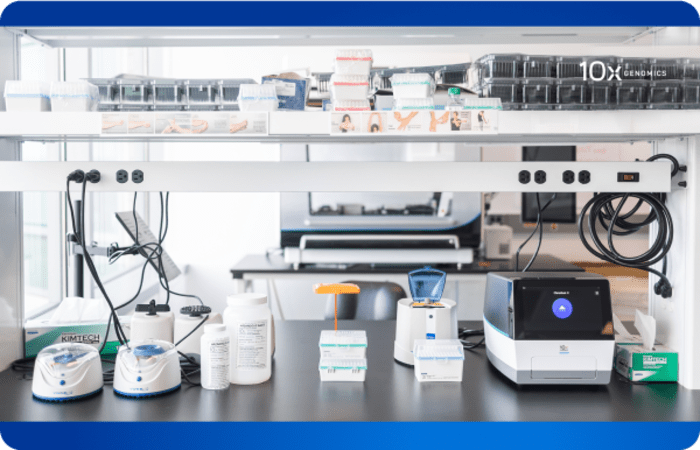A lab workbench with a number of tools for research and a 10x Genomics Chromium X instrument